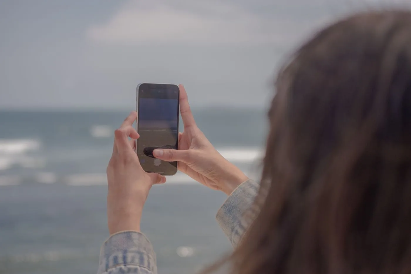 海辺でスマートフォンを構える旅行者の手元