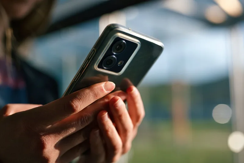 スマートフォンを両手で持つ旅行者の手元