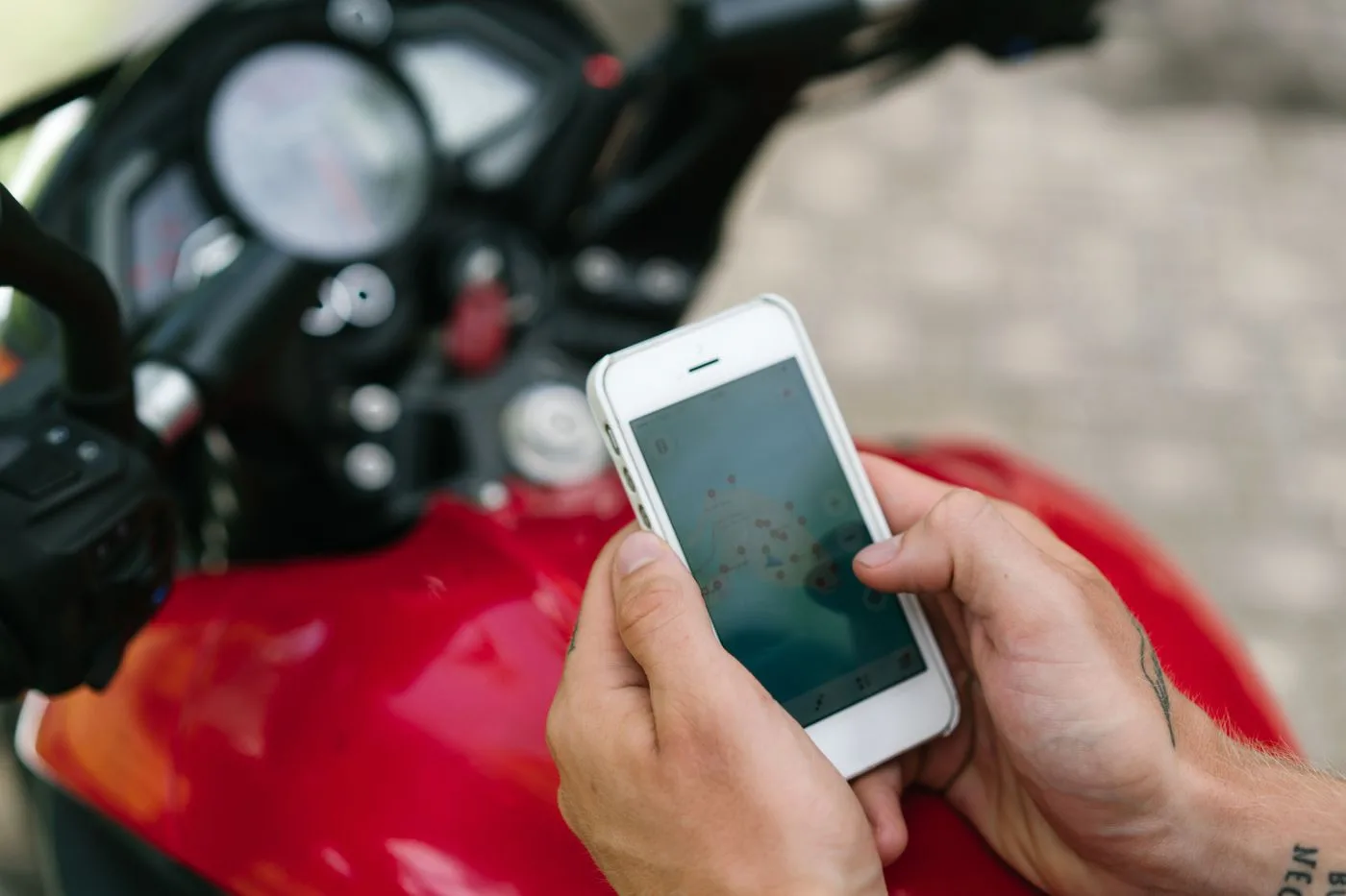バイクの前で、スマートフォンの地図アプリを見ている手元